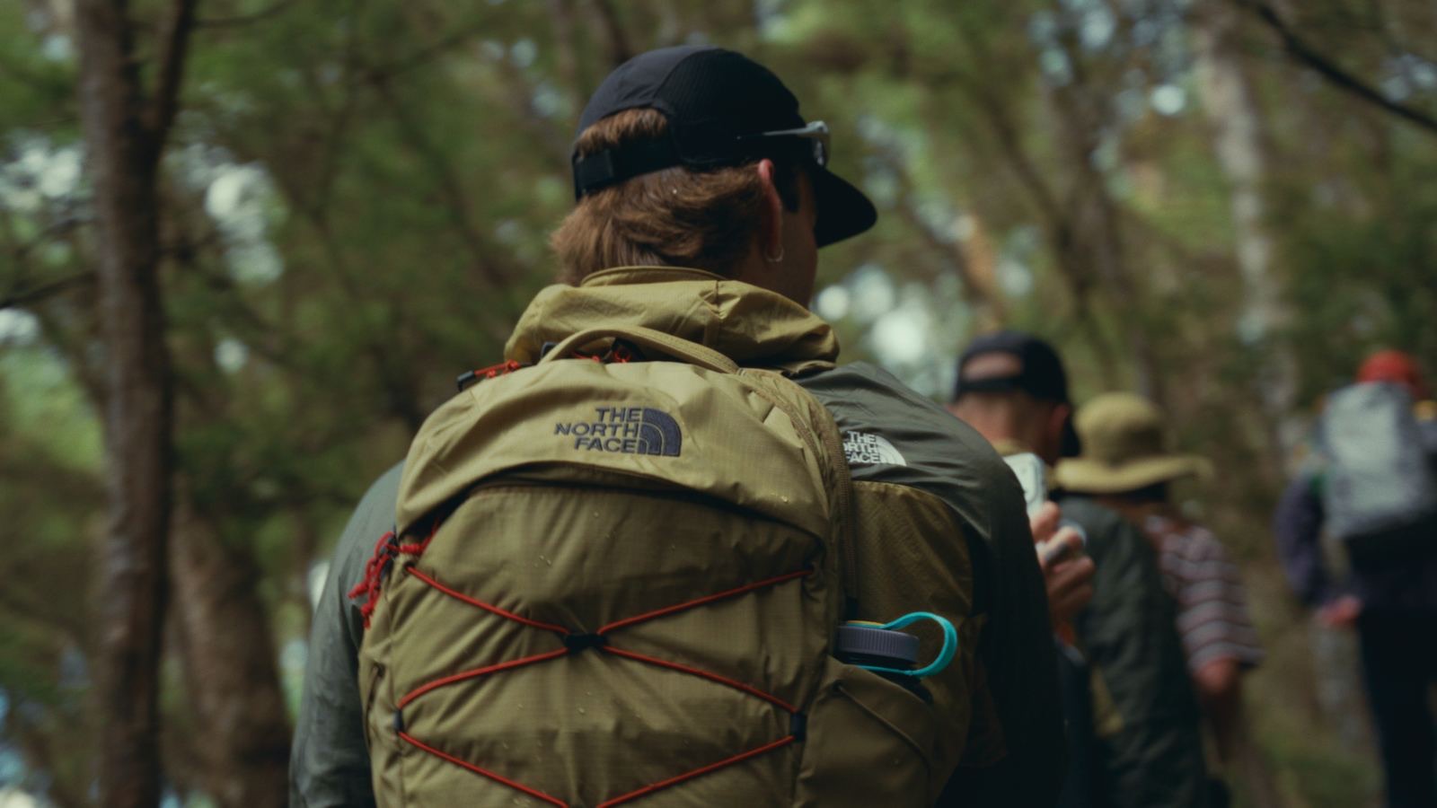A hiker from behind with a green daypack on the trail