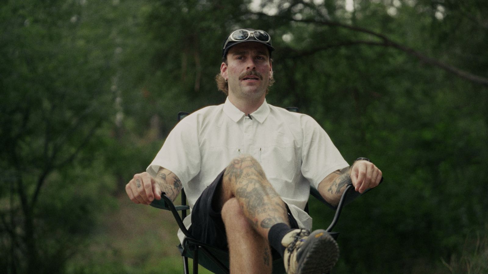 A hiker in a white shirt sitting back in a camp chair