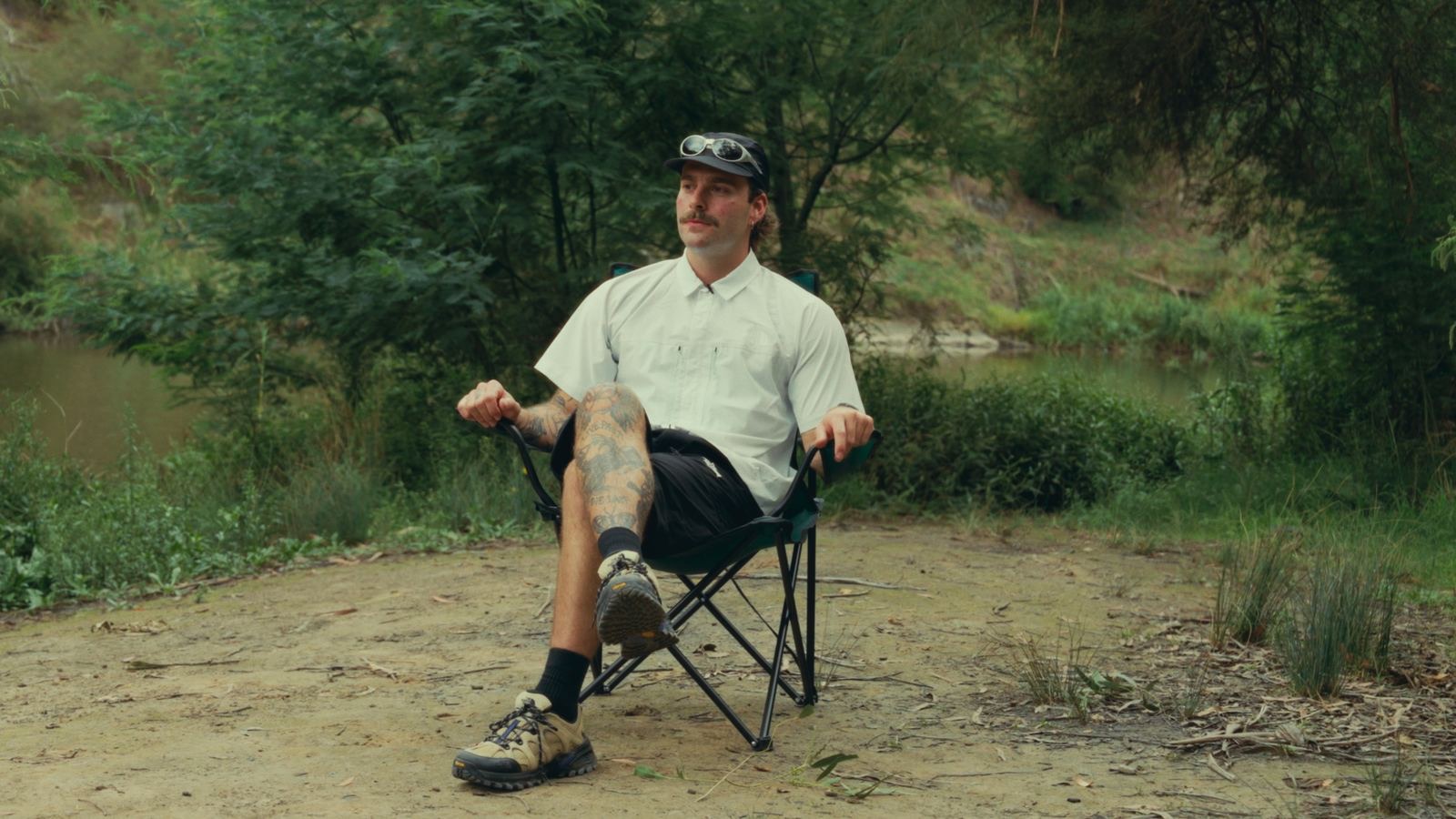 A hiker sitting back in a camp chair beside the river